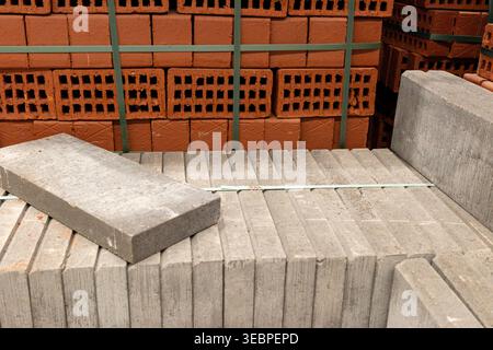 tacked concrete paving slabs with red bricks in construction yard, outdoor material storage. Concept: building supply logistics Stock Photo