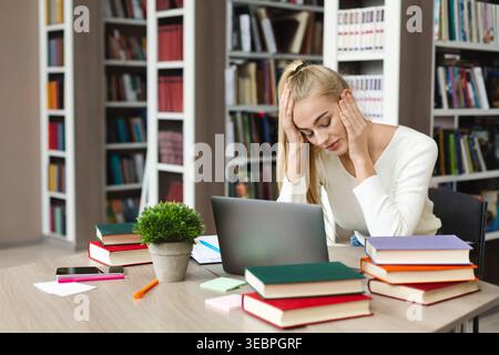 Student Struggles With Assignments in a Library Setting Surrounded by Books Stock Photo