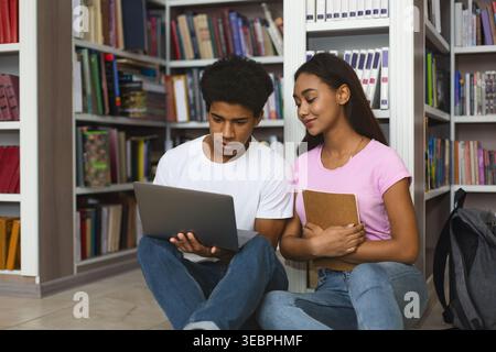 Students Collaborating on a Project While Seated on the Library Floor in a Cozy Learning Environment Stock Photo
