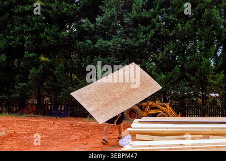 Contractor is moving large plywood at construction site during new home project Stock Photo