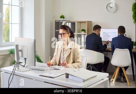 Professional female accountant analyzing financial reports at computer in office Stock Photo