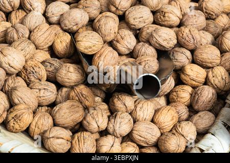 Pile of whole walnuts in shells inside a wicker basket with a metal scoop Stock Photo