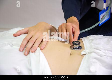 Doctor examining patient abdomen using a stethoscope for diagnosis Stock Photo