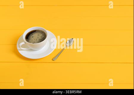 Cup of Coffee with Spoon on Yellow Wooden Background Stock Photo