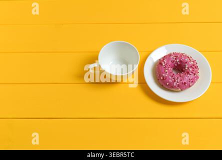 Empty White Cup and Pink Donut on Yellow Wooden Background Stock Photo