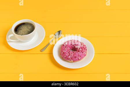 Coffee and Pink Donut with Spoon on Yellow Wooden Background Stock Photo
