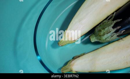 Sliced Eggplant Halves in Clear Glass Bowl on Teal Background — Fresh Aubergine Food Photography Stock Photo