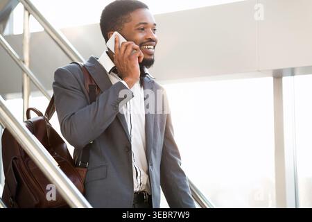 Businessman in Suit Smiles While Talking on Phone During Morning Commute at Modern Office Stock Photo