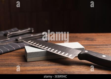 Sharpened knife and whetstone on wooden table. Space for text Stock Photo