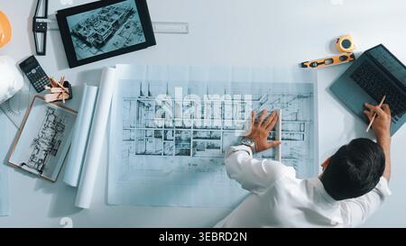 Top view of smart civil engineer drawing and measuring blueprint by using ruler. Aerial view of architect scatch building project plan at meeting Stock Photo