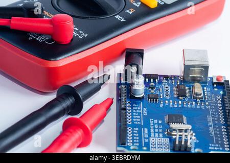 Multimeter with measurement probes and electronics board on a white background Stock Photo