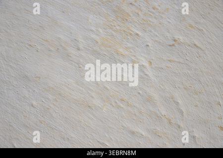 White plastered wall texture with subtle yellow undertones and rough brushstroke details, ideal for graphic design backdrops and minimalist overlays. Stock Photo