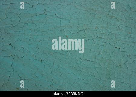 Cracked turquoise paint texture on a solid surface, featuring a complex network of small fractures and a weathered teal patina, suitable for vintage o Stock Photo
