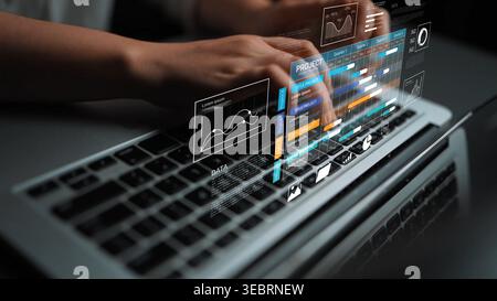 Close-up of hands typing on a laptop keyboard with digital holographic interface displaying graphs and data analytics, representing modern technology Stock Photo