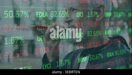 Speaking mature man in dark jacket holding phone to mouth on city street, stock tickers overlay Stock Photo