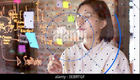 Marking woman in button-up and glasses at office glass board with post-its, marker and blue overlay Stock Photo