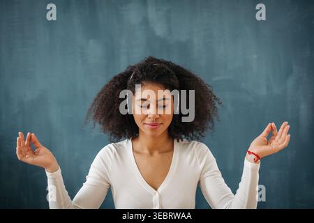 Woman listening to music and meditating with closed eyes in calm focused pose. Stock Photo
