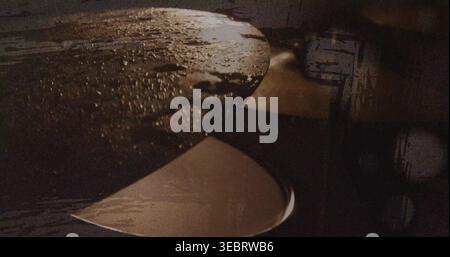 Showing two overlapping metal spoons resting on dark tabletop with water drops and warm highlights Stock Photo