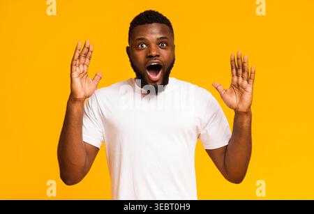 Man Expressing Surprise and Excitement Against a Bright Yellow Background Stock Photo