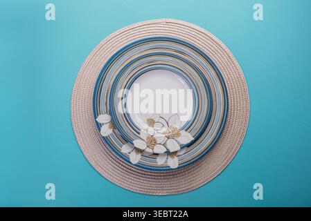 Overhead studio shot features stacked, patterned plates on a woven mat. Plates showcase blue, white, and gold. Commercial use for table setting or pre Stock Photo