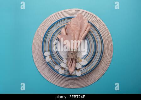 Overhead studio shot showcases a set of vintage plates and a pink linen napkin set on a blue surface. Soft, diffused light highlights textures. Perfec Stock Photo