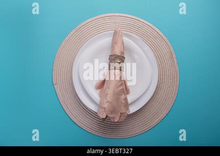 Still life composition. Plate with beige napkin and decorative ring holder, on matching placemat. Soft neutral tones with textured fabrics against a b Stock Photo