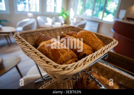 Wicker basket of pastries in sunlit cafe, Antibes, France morning Stock Photo