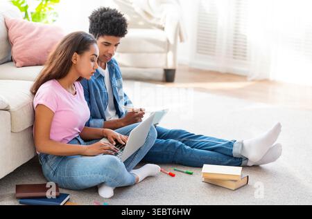 Young Couple Collaborating on School Project While Sitting on Living Room Floor Stock Photo