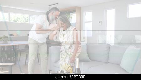 Surprising couple sharing moment in bright living room, with birthday cake, champagne Stock Photo