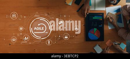 A top-down view of a wooden table with charts and diagrams representing agile project management, showcasing teamwork and strategic planning among Stock Photo