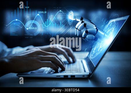 A close-up view of a human hand typing on a laptop, complemented by a robotic finger pointing at a digital interface, showcasing technology and Stock Photo