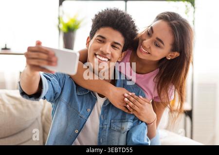 Young Couple Enjoying a Playful Moment Taking a Selfie at Home in Natural Light Stock Photo