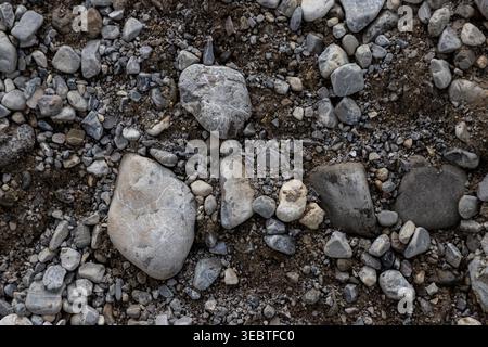 Natural pebble and gravel texture with mixed stones, earth, and rough outdoor surface, suitable for background, pattern, or design use. Stock Photo