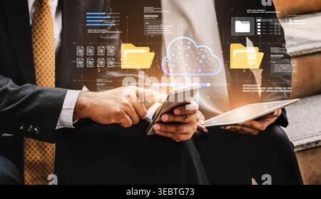 Professionals navigate digital communication using devices in a modern business setting while visual elements depict cloud technology and data Stock Photo