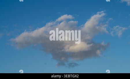Single dramatic cumulus cloud against vivid blue sky, weather background Stock Photo