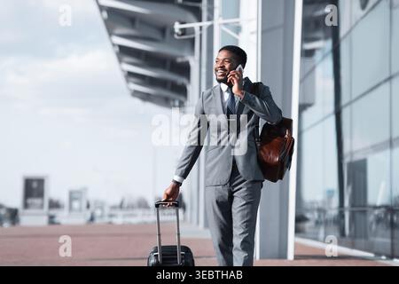 African Man Walking With Luggage And Talking On Phone Stock Photo