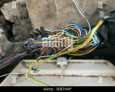 A close-up view of a tangled bundle of multicolored telecommunication cables inside a concrete shaft. Stock Photo