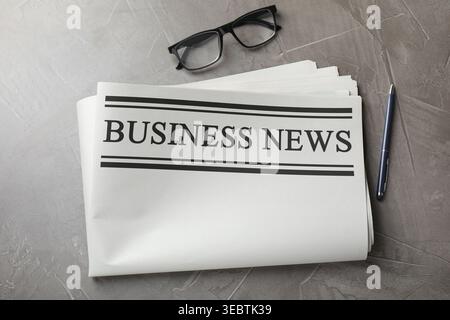 Newspaper, pen and glasses on grey table, flat lay Stock Photo