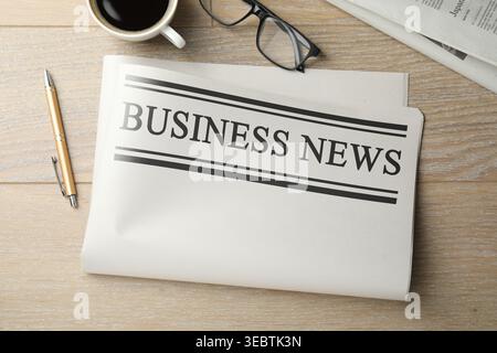 Newspaper, coffee, glasses and pen on wooden table, flat lay Stock Photo