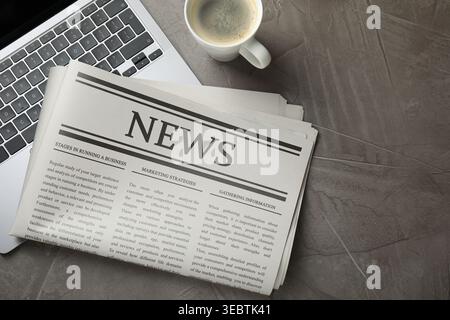 Newspaper, laptop and coffee on grey table, flat lay Stock Photo