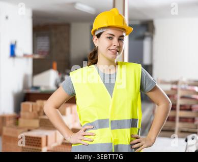 Young woman construction worker standing inside apartment Stock Photo