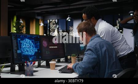 System administrators in office working together to block hacker intrusion, brainstorming. IT startup coworkers colleagues coordinating incident response for scammer attacks Stock Photo