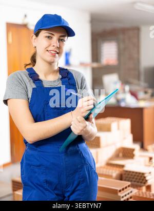 Young woman construction worker standing inside apartment Stock Photo
