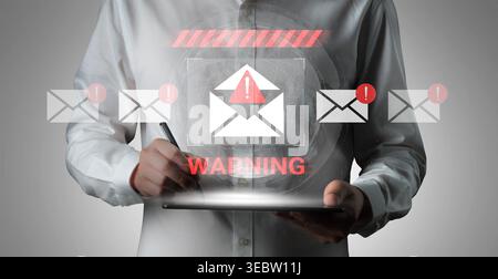 Man in White Shirt Holding Tablet, Displaying Warning Sign for Cybersecurity Threats with Email Icons in Background Gantry. Stock Photo