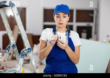Female construction worker using smartphone in apartment Stock Photo