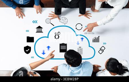 A dynamic office scene illustrating teamwork around a table with cloud technology concepts, showcasing data management and collaborative planning for Stock Photo