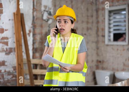 Woman talking on phone at building site Stock Photo