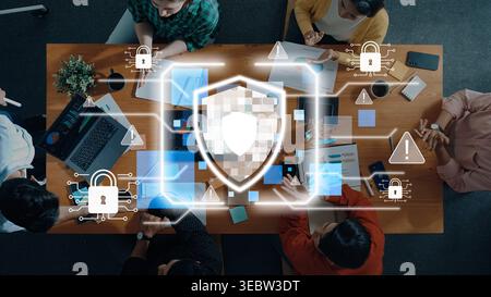 A diverse team collaborates in a modern office setting, focusing on cybersecurity with digital icons illustrating data protection and privacy Stock Photo