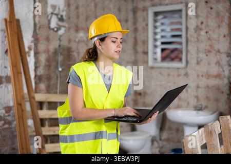 Female civil engineer using laptop at construction site indoors Stock Photo