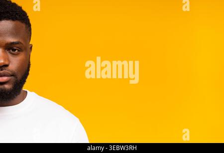 A Young Man Stands Against a Bright Yellow Backdrop, Wearing a Plain White Shirt Stock Photo